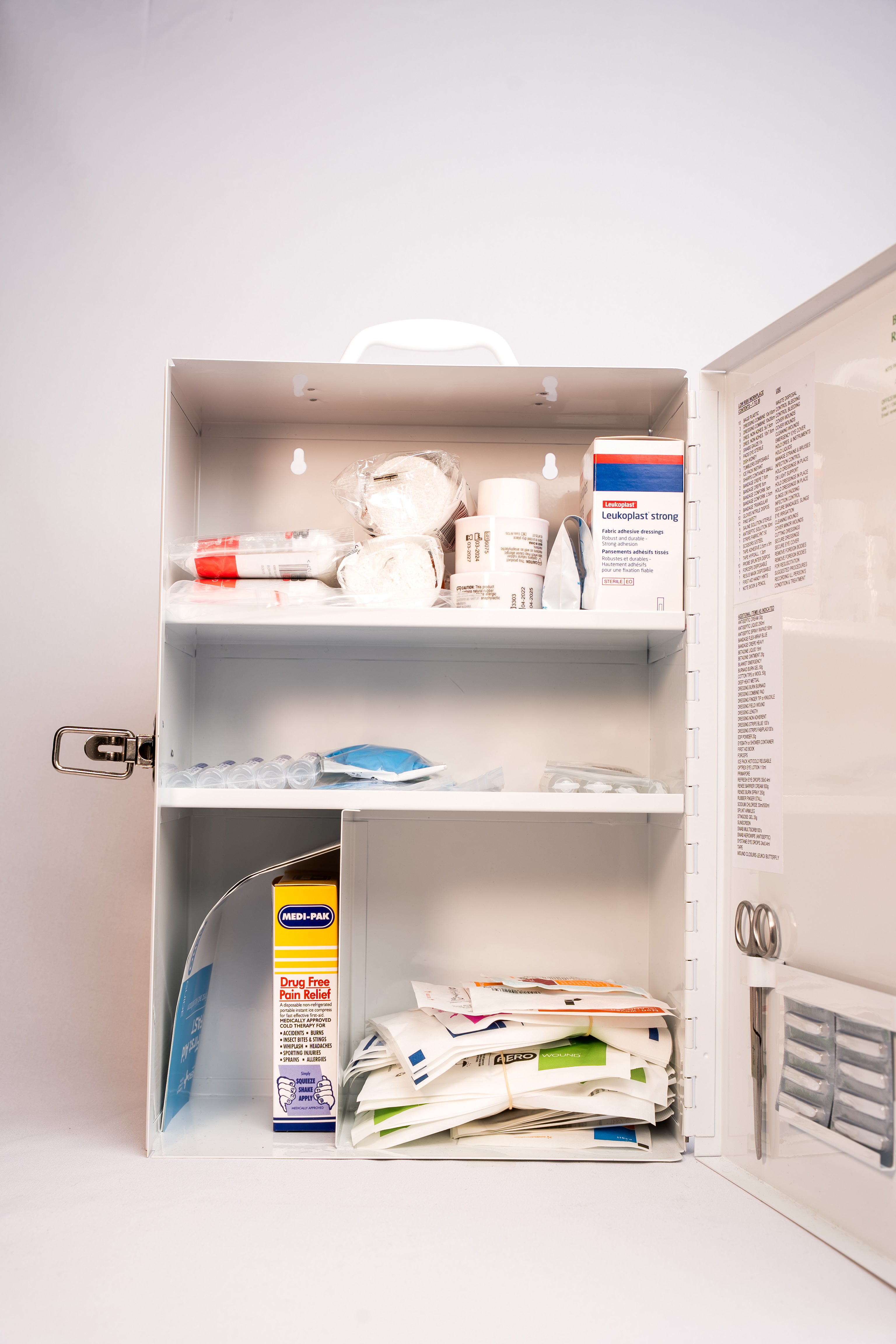 Open first aid cabinet with various supplies on a white background
