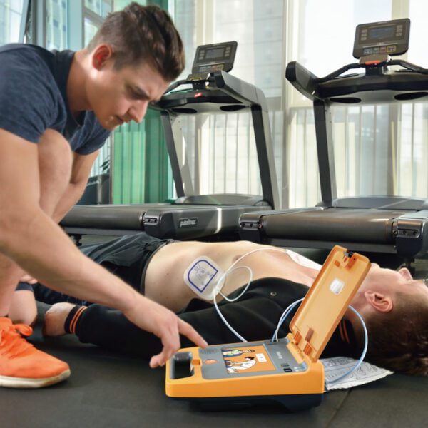 Person using a defibrillator on another person in a gym setting