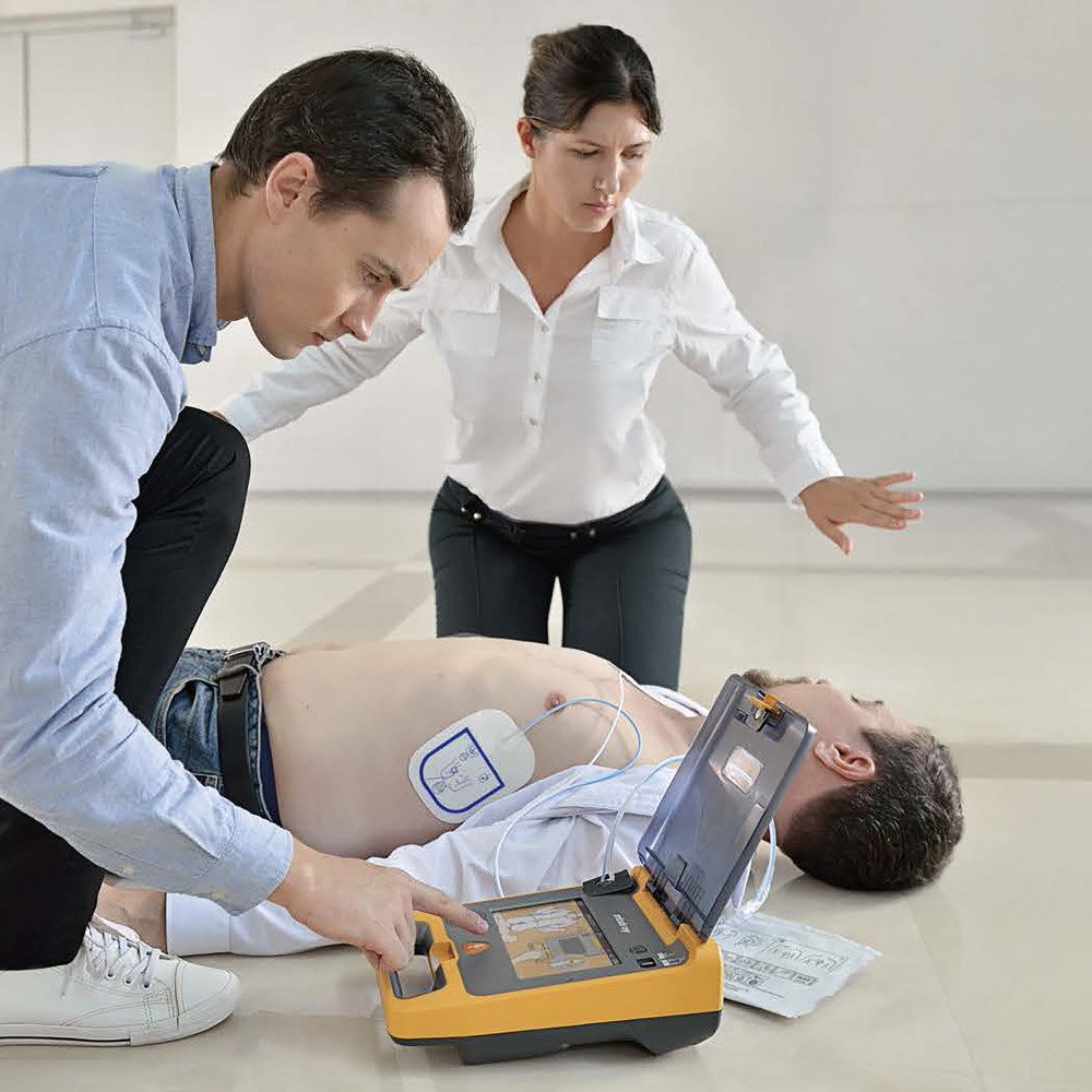 Two people performing CPR on a person with an automated external defibrillator.