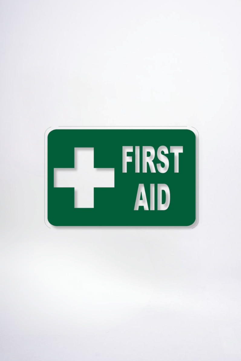 Green sign with white cross and 'First Aid' text on a white background